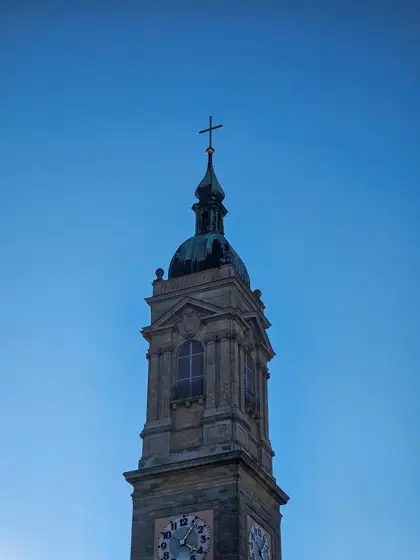 Torre histórica y remate escultórico contra el cielo.