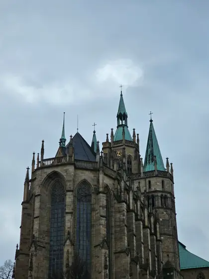 Ábside gótico y contrafuertes bajo un cielo nublado.