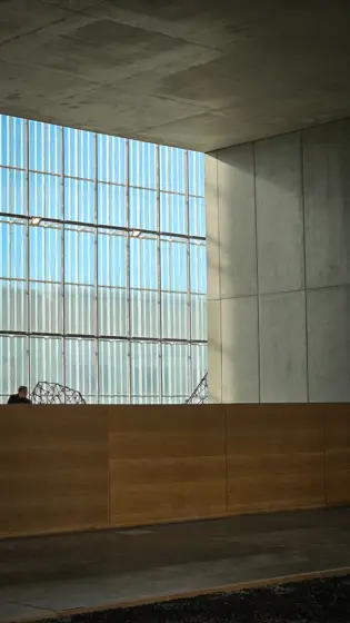 Un ventanal reticulado iluminando el interior de hormigón.