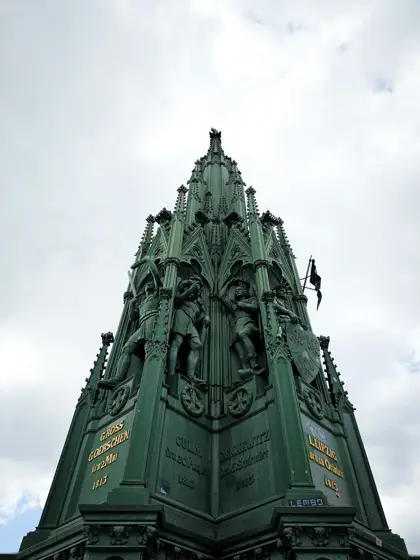 Aguja verde y ornamento sobre el remate de una torre.