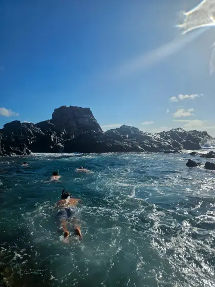 Rocas, agua y presencia humana en el borde costero.