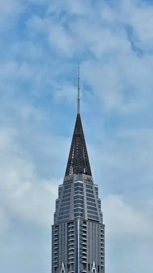 Torre escalonada y remate en aguja sobre el cielo.