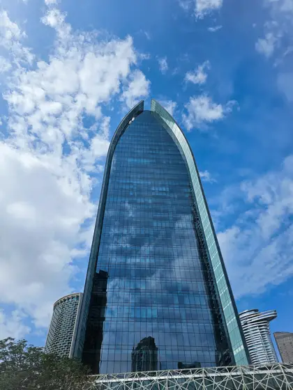 Una fachada curva emergiendo detrás de un conjunto de edificios.