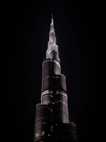 La aguja iluminada de una torre frente al negro del cielo.