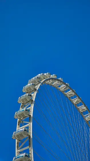 El arco de una rueda panorámica dibujando el cielo.