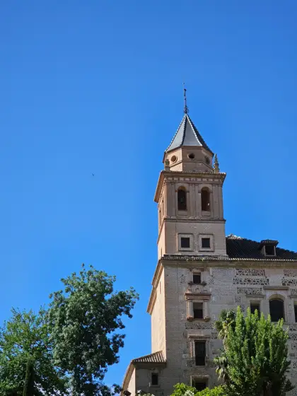 Torre histórica recortada entre árboles y cielo.