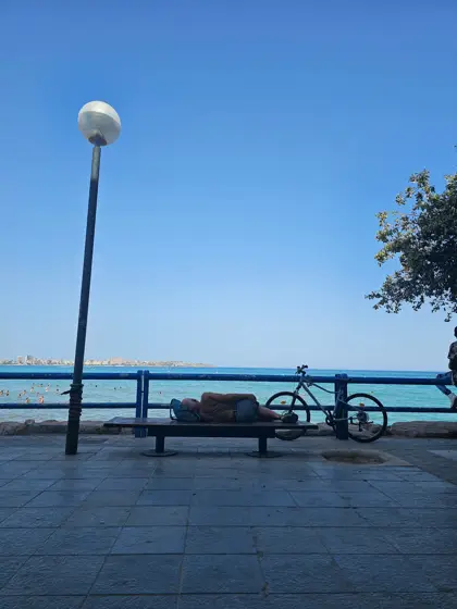 Una luminaria y un banco frente al horizonte marino.