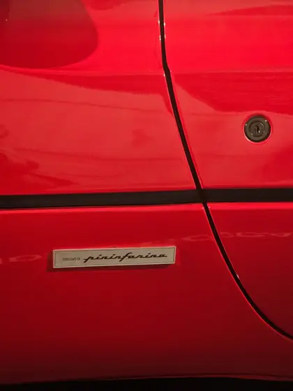 Un detalle de carrocería: líneas, reflejos y superficie roja.