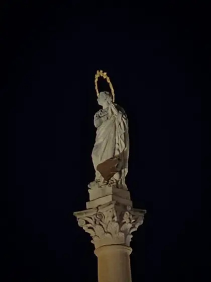 Escultura de piedra aislada sobre el cielo oscuro.