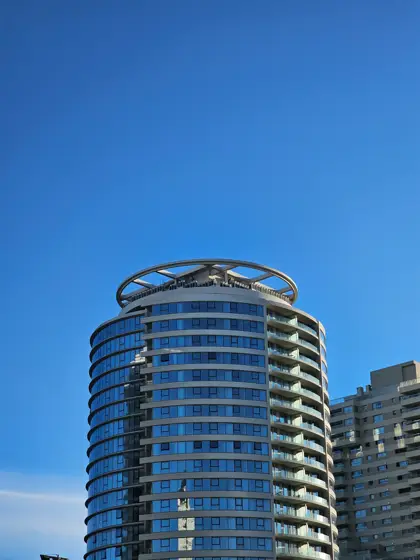 Torre de balcones curvos recortada contra el cielo azul.