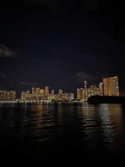 Reflejos de edificios iluminados sobre el agua nocturna.